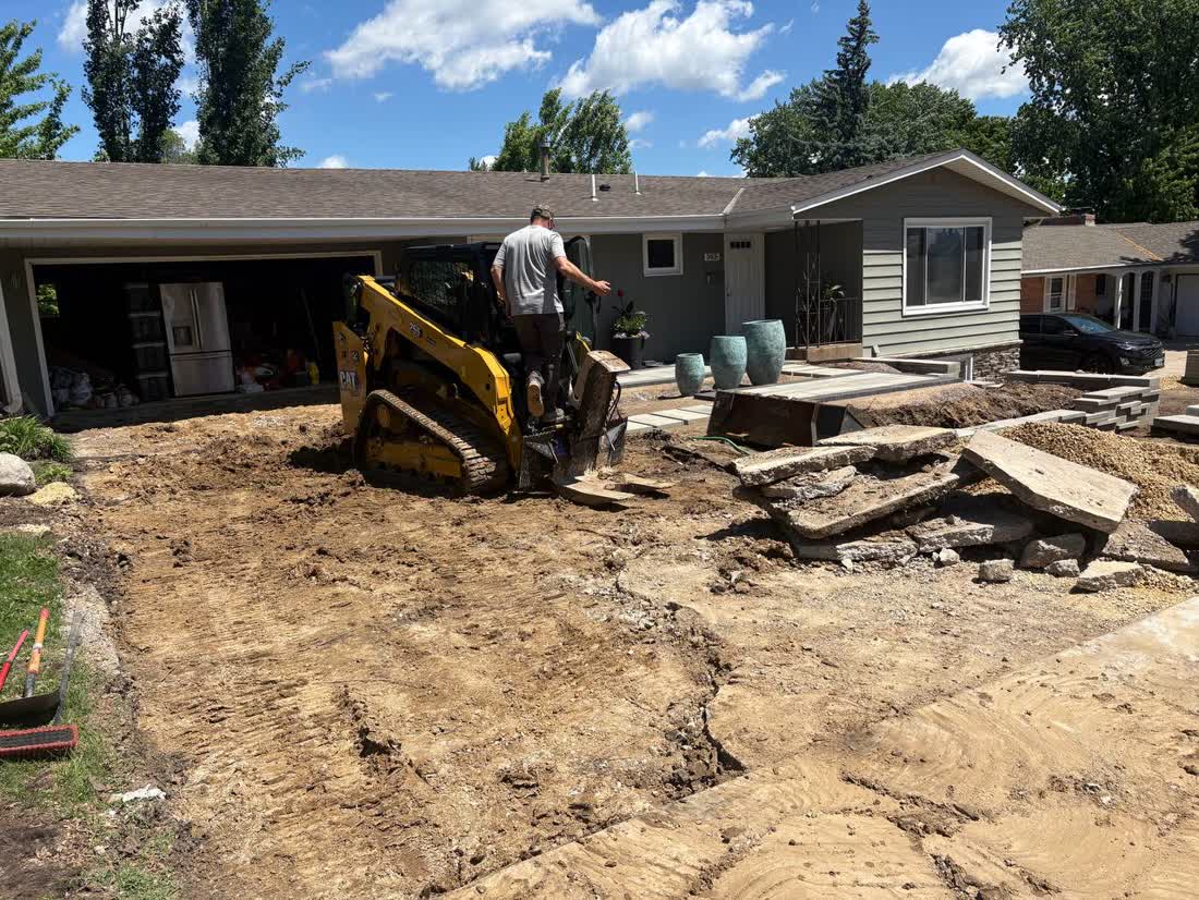 Cat skid steer mid-teardown on a Twin Cities driveway demolition