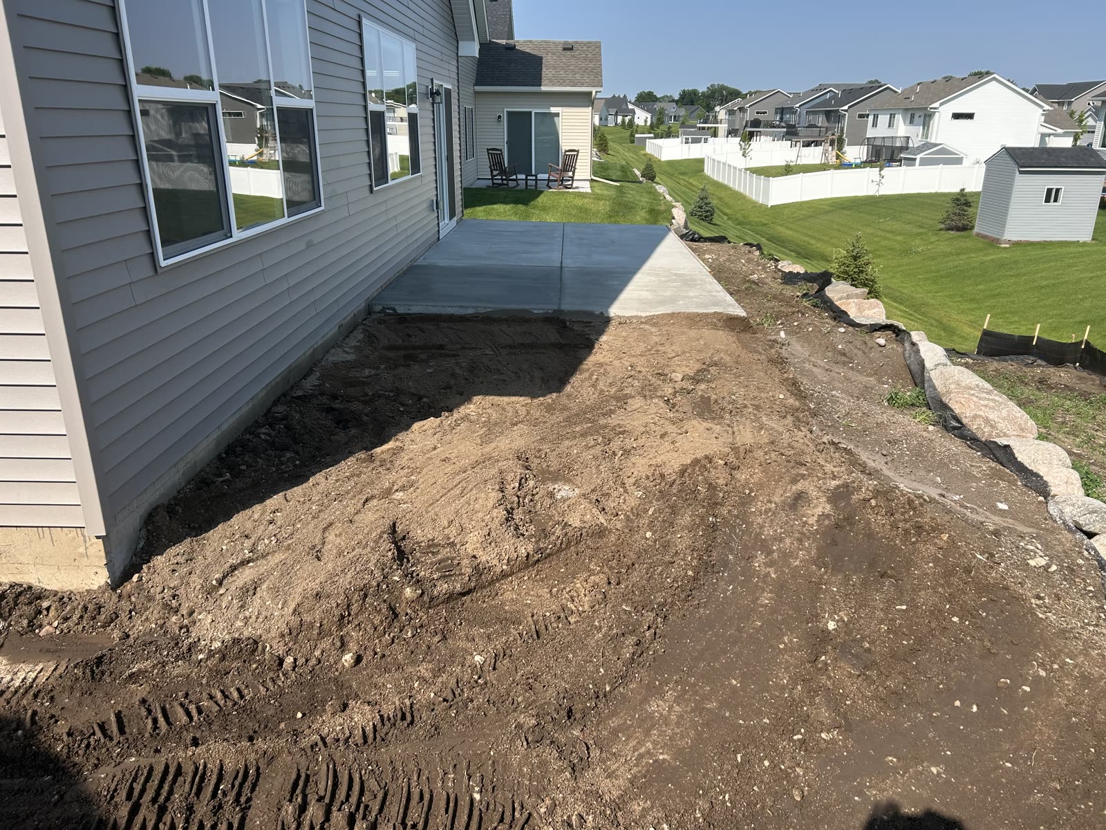 Concrete patio slab demolition progress, broken slab pieces and skid steer, Minneapolis MN