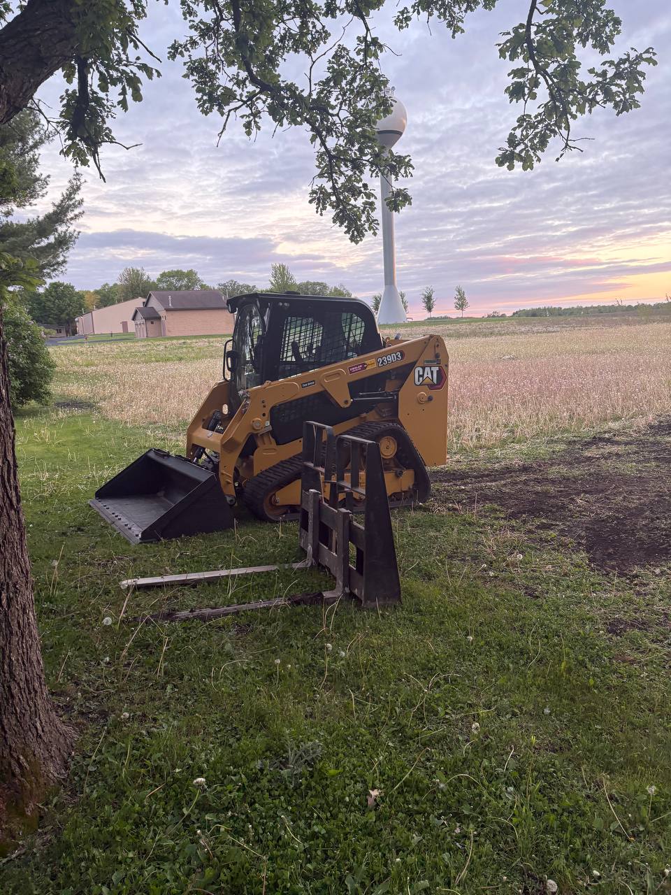 CAT 239D3 skid steer staged with bucket and pallet fork attachments at Twin Cities job site