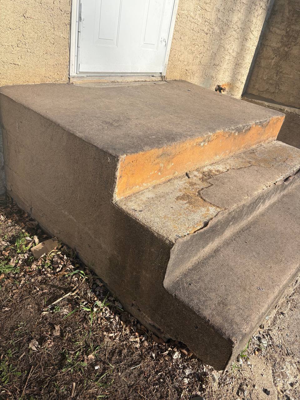 Deteriorated concrete back stoop with paint flaking and cracks at Minneapolis residence