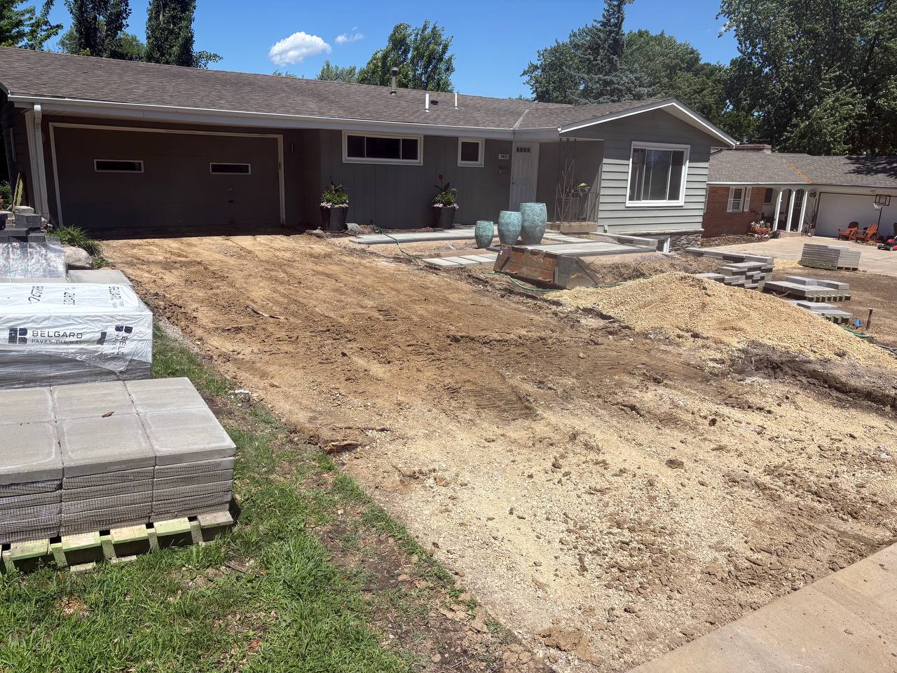 Driveway graded clean with Belgard paver pallets staged for install, Twin Cities