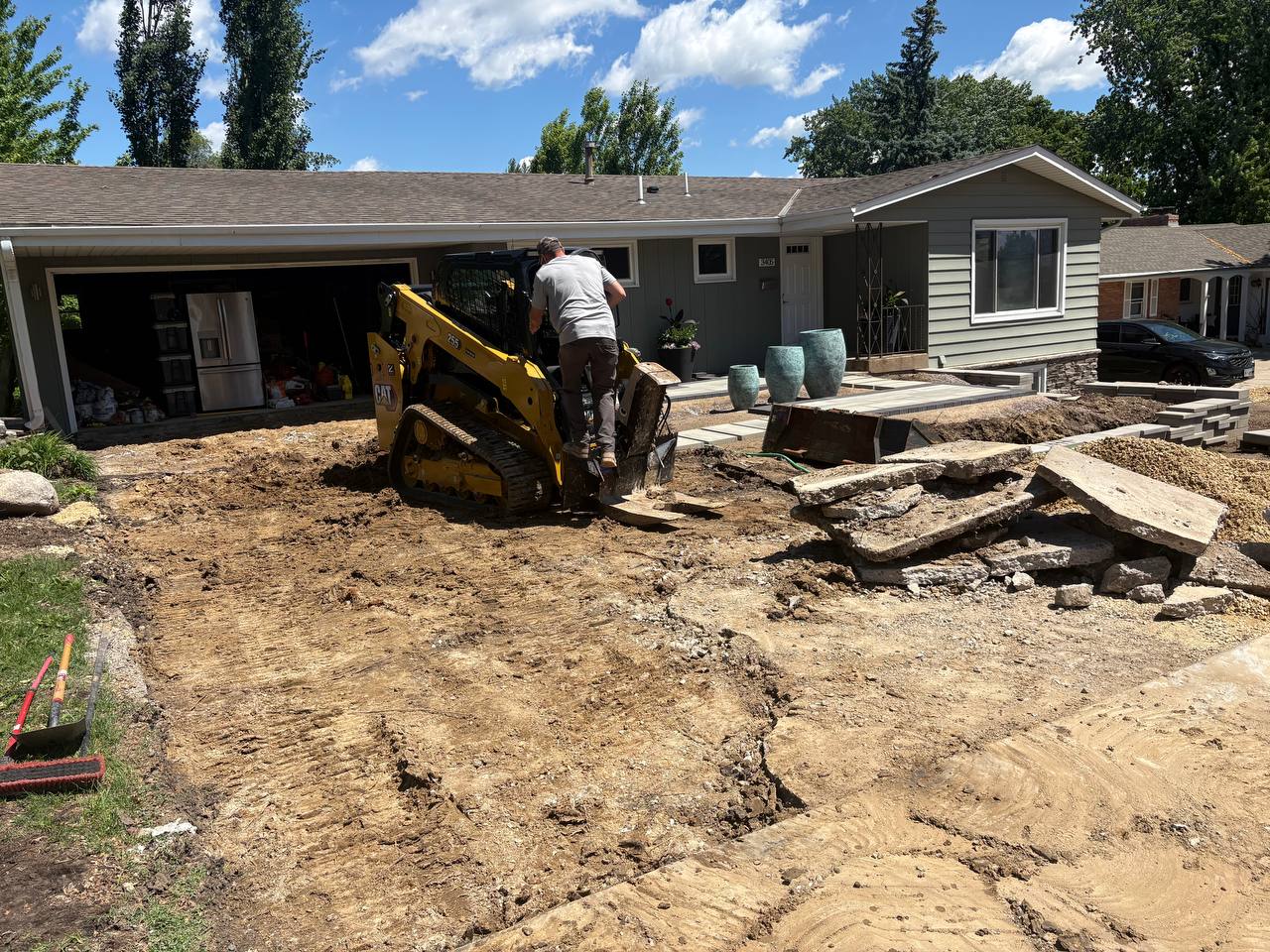 CAT 255 skid steer ripping out concrete driveway at Minneapolis ranch home