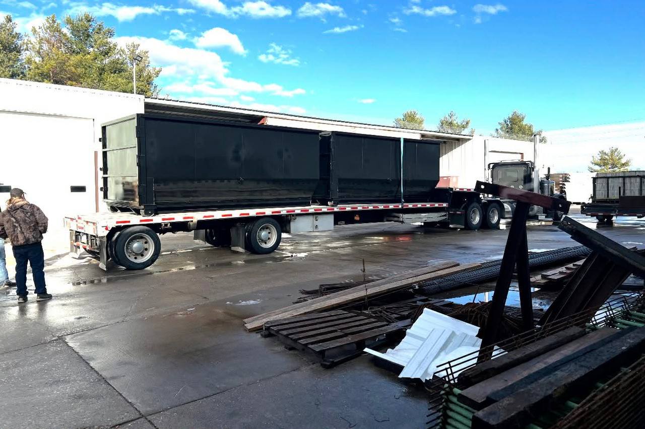 Flatbed truck delivering roll-off dumpster to Twin Cities customer site