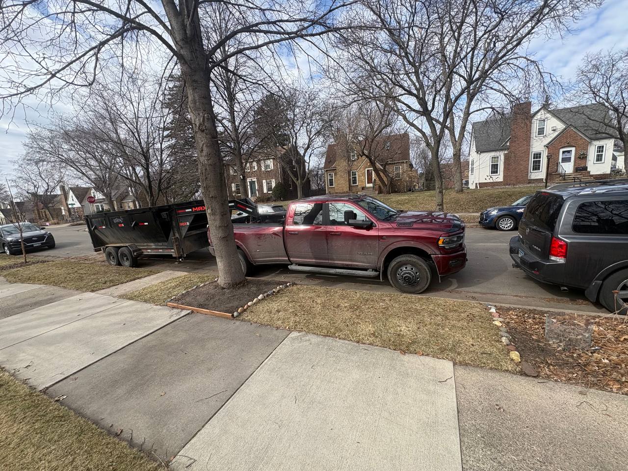 Red Ram 3500 dually with dump trailer parked curbside at Twin Cities demo job