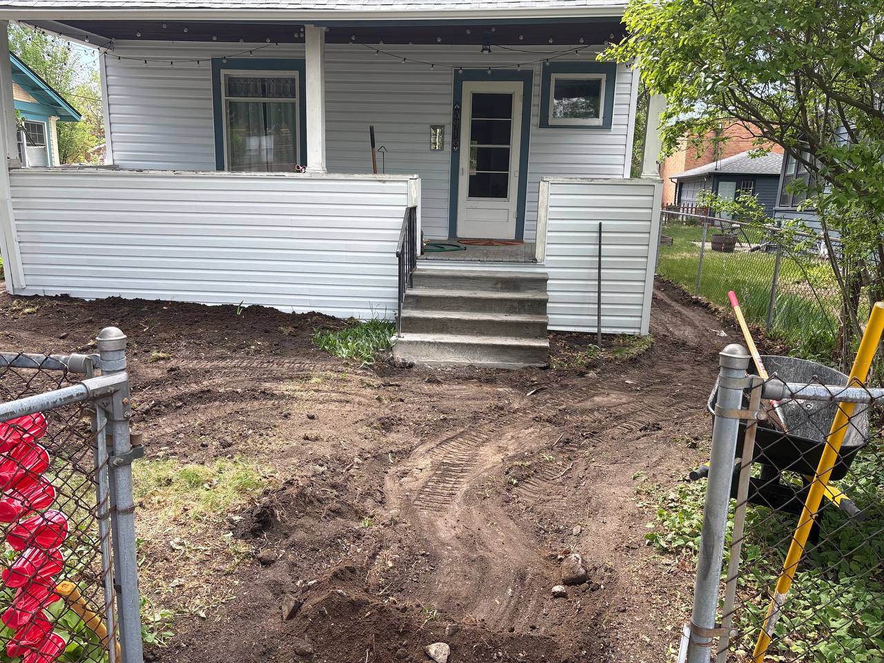 Residential asphalt driveway removal in progress, chunks loaded into wheelbarrow