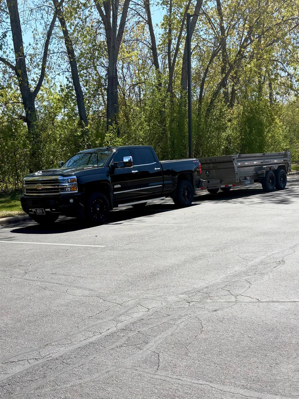 Black Chevy Silverado pulling fully loaded dump trailer with concrete debris, Twin Cities
